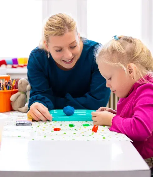 Ergotherapeutin übt mit einem Kind am Tisch